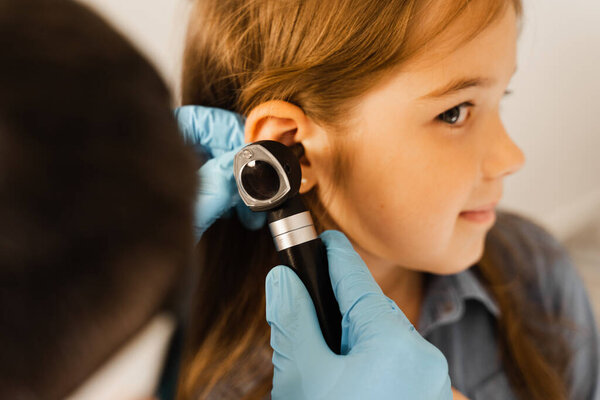 Close-up examination of childs ear with otoscope. Otoscopy. Visit to ENT doctor and consultation