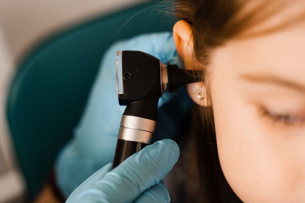 Close-up examination of childs ear with otoscope. Otoscopy. Visit to ENT doctor and consultation