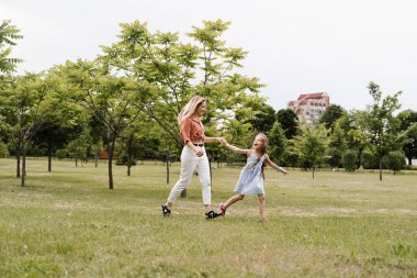 Anne ve kızı parkta koşup eğleniyorlar. Aile değerleri ve gelenekler. Mutlu bir çocukluk dönemi. Anne kızıyla oynuyor.