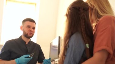 4K video doktoru otoskopla anne ve kızı için danışmanlık yapıyor. Otoskopi. Tedavi kulak ağrısı