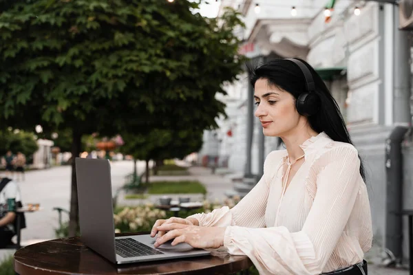 Girl with vitiligo skin pigmentation on the hands working on laptop online and listen music with headphones. Skin seasonal disease