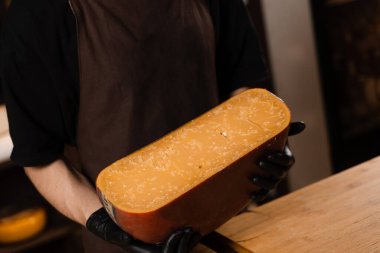 Peynirli şarap garsonunun elinde sınırlı gouda peyniri. Atıştırmalık lezzetli bir parça peynir.