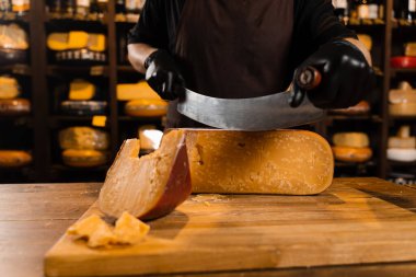 Peynirli şarap garsonu sınırlı gouda peynirini bıçakla kesiyor. Atıştırmalık lezzetli bir parça peynir.