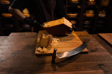 Peynirli sommelier dilimlenmiş peynirli gouda peyniri ve dilimleyici. Dükkanda peynir dilimliyorum. Atıştırmalık lezzetli bir parça peynir.
