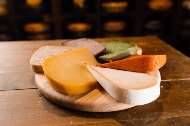 Genç Gouda, genç keçi, lavanta peyniri ve masada yeşil ve kırmızı pesto peyniri karışımı. Peynir dükkanı reklamı için yaratıcı bir fikir.