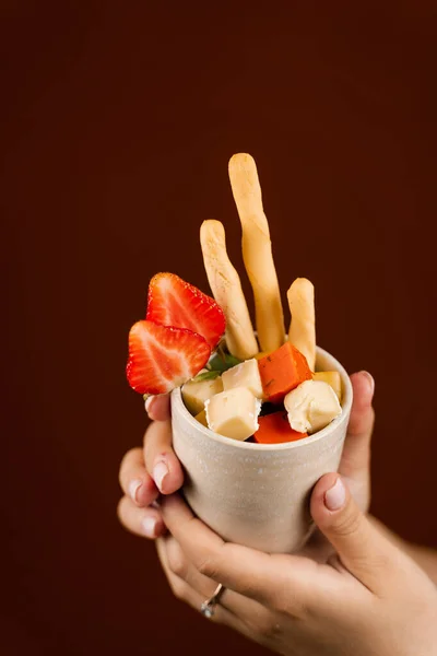 Creative mix of cheeses, grissini sticks and strawberry in cup. Creative idea for advertising a cheese shop