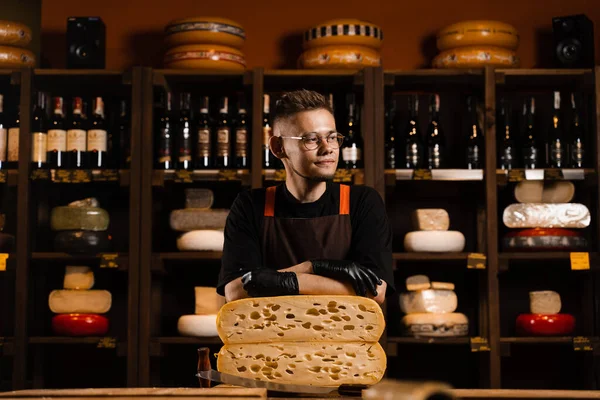 Professional cheese sommelier in food shop. Worker of cheese store with limited maasdam natural aged
