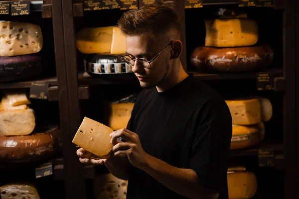 Handsome buyer in cheese shop looking at limited gouda cheese. Snack tasty piece of cheese for appetizer