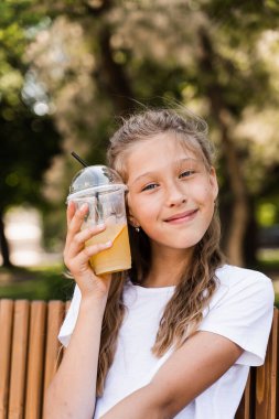 Açık havada limonata kokteyli. Portakallı limonata ve gülücükler taşıyan mutlu bir kız.