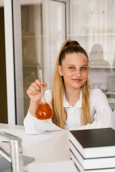 Chemistry lesson at school. Girl with flask is studying in chemistry classroom. Schoolgirl holding flask with chemical in the laboratory