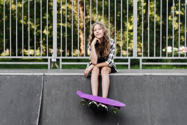 Kaykay sporu rampasında oturan kaykaylı aktif bir çocuk. Ekstrem spor yaşam tarzı. Spor çocuk mağazası için yaratıcı reklam