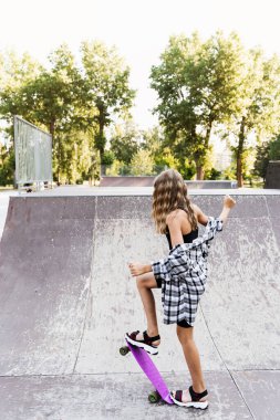 Genç kız kaykay parkında kaykay yapmaya hazır. Çocuklar için spor malzemeleri. Aşırı yaşam tarzı.