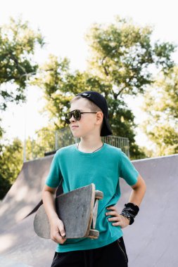 Happy young child boy with skate board on playground and smile. Extreme sport lifestyle. Smiling child with skate board posing on sport ramp