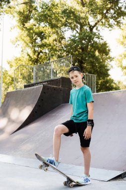 Teenager boy ready for ride on skate board on skateboard park playground. Sports equipment for kids. Extreme lifestyle