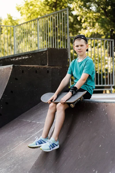 Child boy with skate board. Young boy with skate board sitting on sport ramp on skate playground. Extreme lifestyle. Creative advert for skate or penny board shops or stores