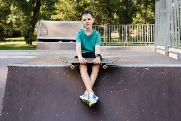 Child boy with skate board. Young boy with skate board sitting on sport ramp on skate playground. Extreme lifestyle. Creative advert for skate or penny board shops or stores