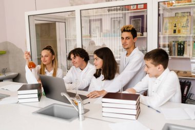 Eğitim. Okulda kimya dersinde kimyasal deneyler. Sınıf arkadaşları test tüpleri tutuyor ve laboratuarda deneyler yapıyorlar.