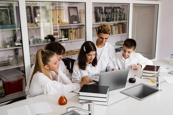 The class is studying in the chemistry lesson at school in the laboratory. Education. The teacher checks the homework in the book. Preparing for experiments