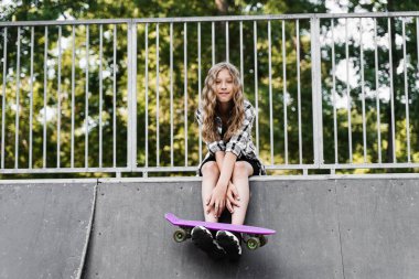 Kaykay sporu rampasında oturan kaykaylı aktif bir çocuk. Ekstrem spor yaşam tarzı. Spor çocuk mağazası için yaratıcı reklam