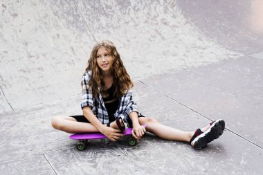 Kaykay parkında spor rampasında oturan çekici çocuk. Kuru tahtayla poz veren aktif bir genç. Aşırı yaşam tarzı.