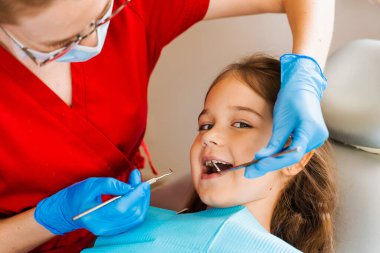 Dişçilere dişçilik danışmanlığında gülümseyen neşeli bir kız çocuğu. Diş hastalıkları. Çocuktaki diş ağrısının tedavisi için pediatrik dişçiye danışma