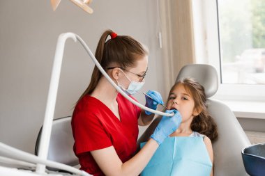 Diş matkabı. Çocuk diş hekiminde dişçi kızın dişlerini deliyor. Çocuk hasta için diş dolgusu
