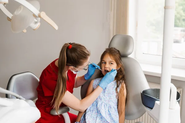 Child girl afraid dentist. Childrens dentist consults frightened kid in dentistry. Treatment of teeth and toothache in children