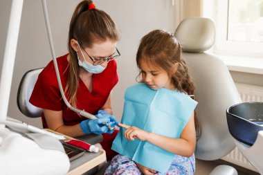 Diş hekimliğindeki çocuk dişleri için profesyonel hijyen. Çocuk için profesyonel diş temizliği. Pediatrik dişçi, diş hekimliğindeki çocuk hastalarını muayene eder ve muayene eder.