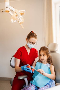Diş hekimi çocuğa diş fırçasının nasıl düzgün kullanılacağını gösteriyor. Çene anatomik model diş fırçalama. Pediatrik dişçi, diş hekimliğinde çocuklara ağız temizliği dersi veriyor.