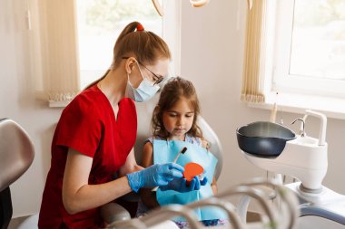 Diş hekimi çocuğa diş fırçasının nasıl düzgün kullanılacağını gösteriyor. Çene anatomik model diş fırçalama. Pediatrik dişçi, diş hekimliğinde çocuklara ağız temizliği dersi veriyor.