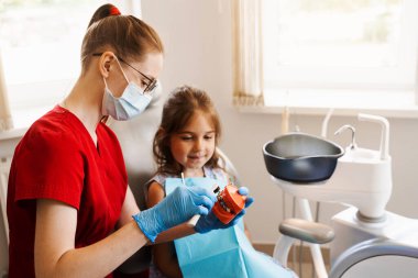 Diş hekimi çocuğa diş fırçasının nasıl düzgün kullanılacağını gösteriyor. Çene anatomik model diş fırçalama. Pediatrik dişçi, diş hekimliğinde çocuklara ağız temizliği dersi veriyor.