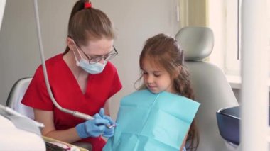 Professional hygiene for teeth of child in dentistry. 4k video. Professional teeth cleaning for child girl. Pediatric dentist examines and consults kid patient in dentistry