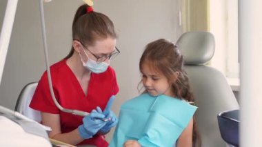 Professional teeth cleaning for child girl. 4k video. Professional hygiene for teeth of child in dentistry. Pediatric dentist examines and consults kid patient in dentistry