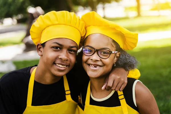 African children cooks in chefs hat and yellow uniforms smiling close-up portrait . African teenager and black girl have fun and cook food