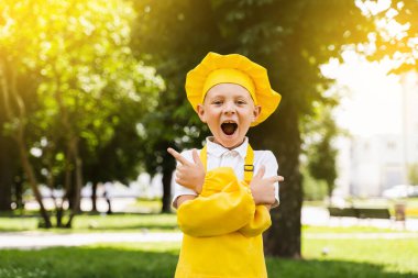 Sağa işaret ediyor. Sarı şapkalı ve önlüklü yakışıklı aşçı çocuk sol ve sağ tarafı işaret ediyor. Yemek dükkanı ve kafe için yaratıcı bir reklam.