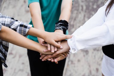 Stack of children hands close-up. Concept of friendship sports support of children. Kids with skateboards and penny boards posing together on sport ramp on skate board playground