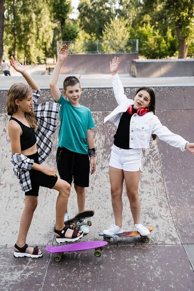 Concept of friendship sports support of children. Kids with skateboards and penny boards stack their hands together and get ready for ride together on sport ramp on skate board playground