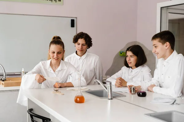 Education. Chemical experiments at a chemistry lesson at school. Children classmates hold test tubes and conduct experiments in the laboratory