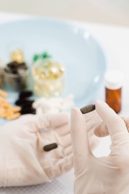 Nutritionist holding biologically active supplements tablets in gloves and help patient to plan daily diet. Pills for weight loss. Recommendation for daily dietary