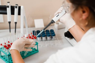 Laboratuvarda mikrodozeri olan bir laboratuvar asistanı kan tahlili yapıyor. Laboratuvarda tıbbi malzemeler. Kan emici bilim adamı kan analizi yapıyor.