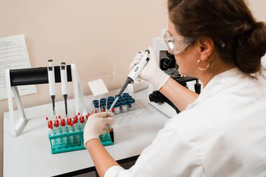 Laboratuvarda mikrodozeri olan bir laboratuvar asistanı kan tahlili yapıyor. Laboratuvarda tıbbi malzemeler. Kan emici bilim adamı kan analizi yapıyor.