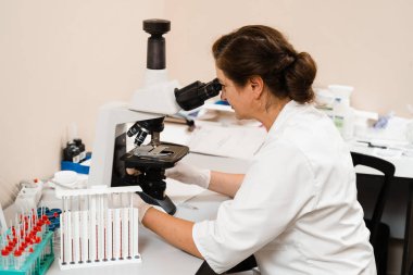 Laboratuvar asistanı mikroskoba bakar ve laboratuvarda kan testi yapar. Bir klinikte hematolojik ve biyokimyasal kan testleri için tıbbi ekipman