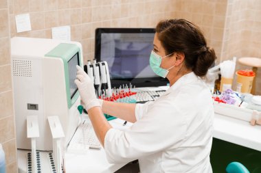 Laboratuvar asistanı kan analizi üzerinde çalışıyor ve laboratuvarda hematolojik analiz yapıyor. Laboratuvarda tıbbi malzemeler var. Kanın biyokimyasal ve hematolojik analizi