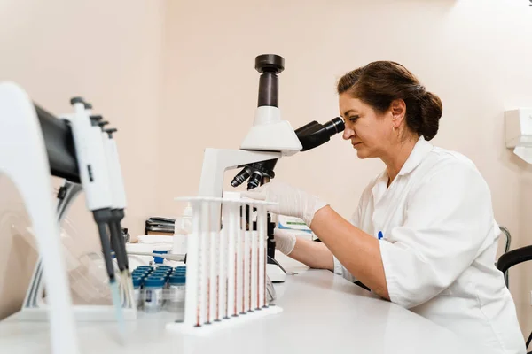 실험실 조수는 현미경을 통하여 실험실에서 검사를 병원에서 생화학 검사를 — 스톡 사진