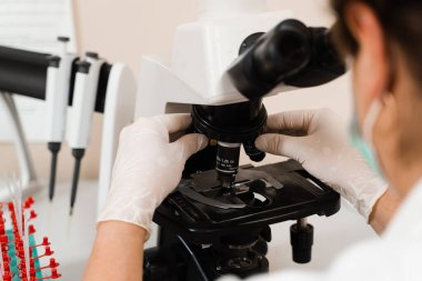 Laboratuvar asistanı mikroskoba bakar ve laboratuvarda kan testi yapar. Bir klinikte hematolojik ve biyokimyasal kan testleri için tıbbi ekipman