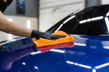Oto servisinde mikrofiberle kurutulan el arabası. Araba yıkadıktan sonra temizlikçi kuru araba.