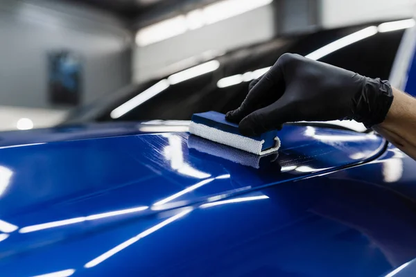 Process of applying ceramic protective coat on body car in detailing auto service. Car service worker apply ceramic coating to protect the car body from scratches