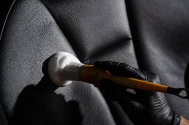 Köpük ve deterjan temizleme işlemi için fırça kullanılıyor. Otomotiv temizleme servisinde çalışan bir işçi. Araç iç dekorasyonu