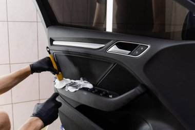 Araba kapısının içindeki fırçayla köpük ve deterjan temizleme işlemi. Araba temizleme servisi. Temizlik işçisi, müşterilerin iç çamaşırlarını yıkıyor.