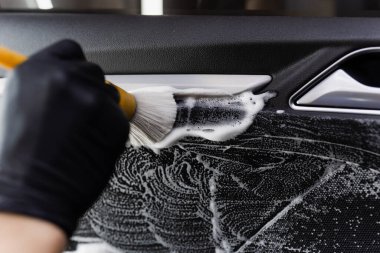 Araba kapısının içinde fırça kullanarak köpük ve deterjan yıkama. Araba temizleme servisi. Temizlik işçisi müşterilerin iç çamaşırlarını otomatik olarak yıkar